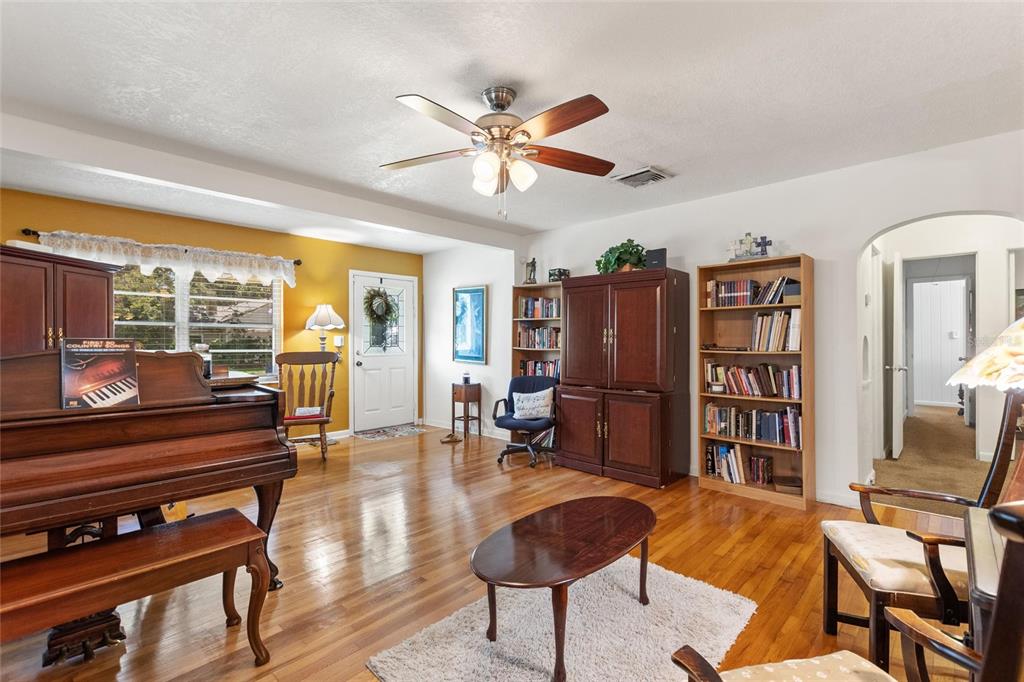 A living room features a piano, hardwood floors, bookshelves, and a ceiling fan — 2230 W CENTRAL AVENUE, WINTER HAVEN, FL