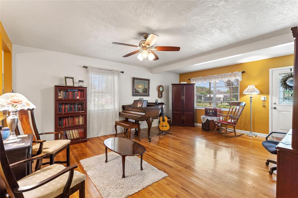 A living room features hardwood floors, a piano, a bookshelf, and a ceiling fan — 2230 W CENTRAL AVENUE, WINTER HAVEN, FL
