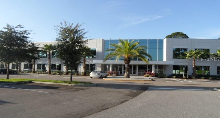 A two-story office building features a glass facade, a central entrance, and a parking lot — 7560 RED BUG LAKE ROAD UNIT 2084, OVIEDO, FL