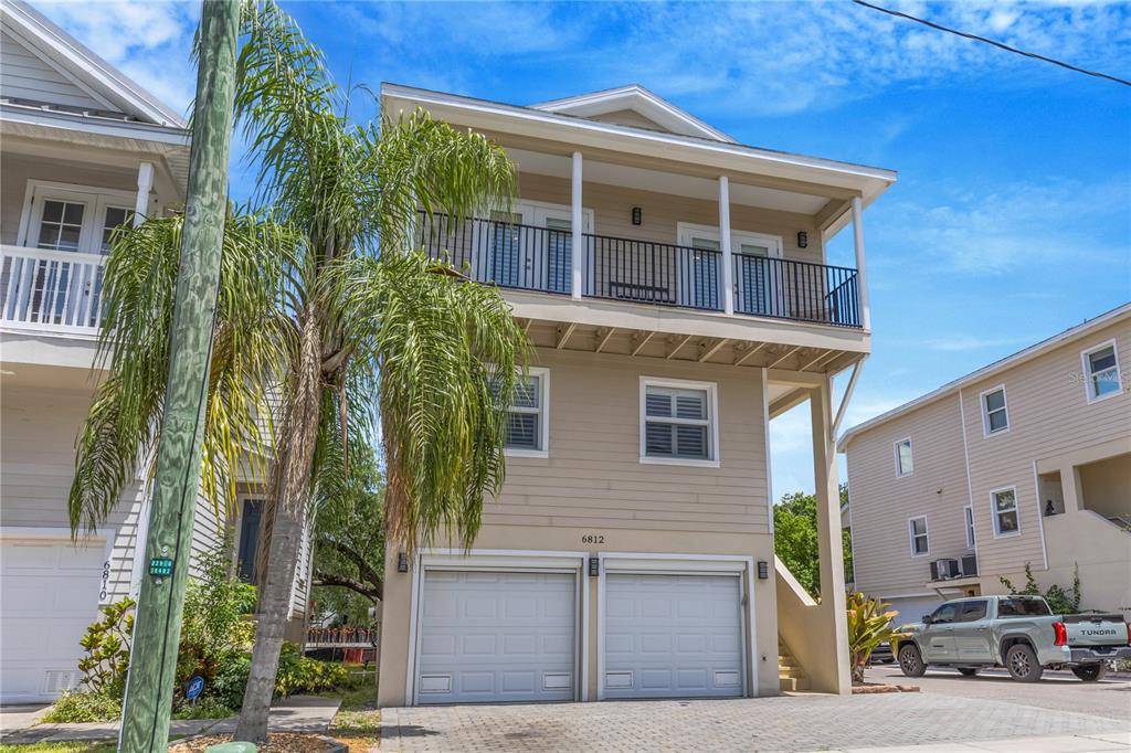 A three-story house with a two-car garage, a second-story balcony, and light-colored siding — 6812 S KISSIMMEE STREET, TAMPA, FL