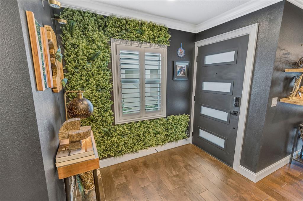 An entryway features dark walls, a green plant wall, a window with shutters, and a door — 6812 S KISSIMMEE STREET, TAMPA, FL