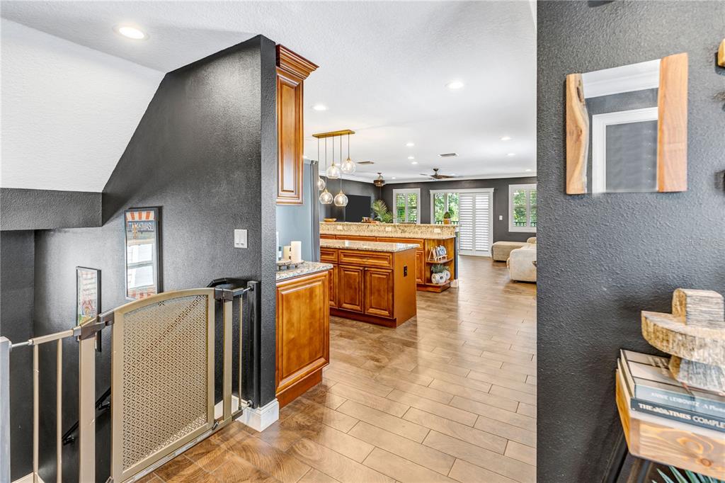 A view from a staircase landing looking into a kitchen with wood cabinets and flooring — 6812 S KISSIMMEE STREET, TAMPA, FL