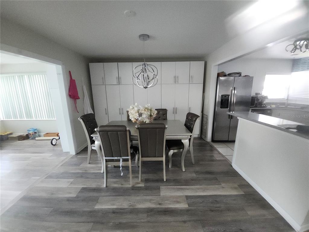 A dining room features a table with six chairs, a modern chandelier, and floor-to-ceiling cabinetry — 4 CHIPPEWAY COURT, PALM COAST, FL