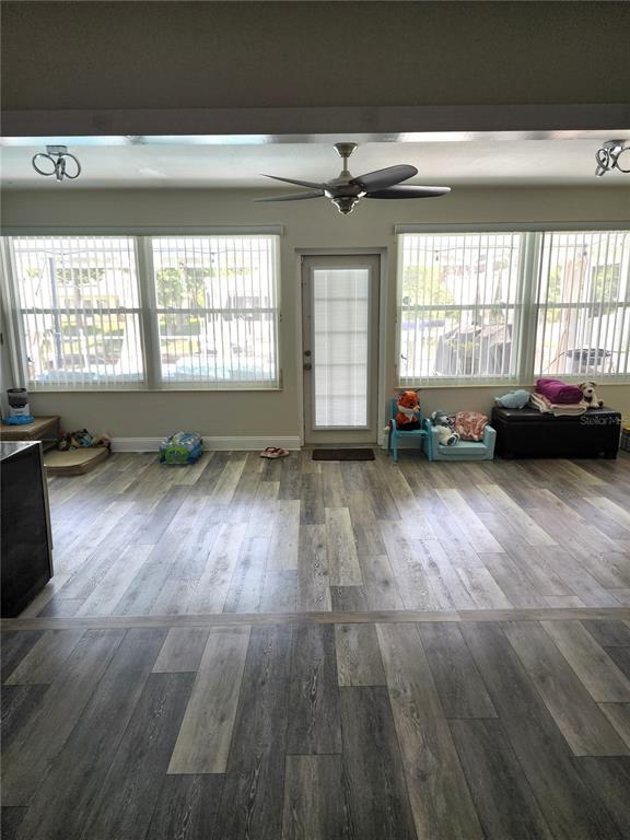 A sunroom with wood-look vinyl flooring, a ceiling fan, and large windows flanking a door — 4 CHIPPEWAY COURT, PALM COAST, FL