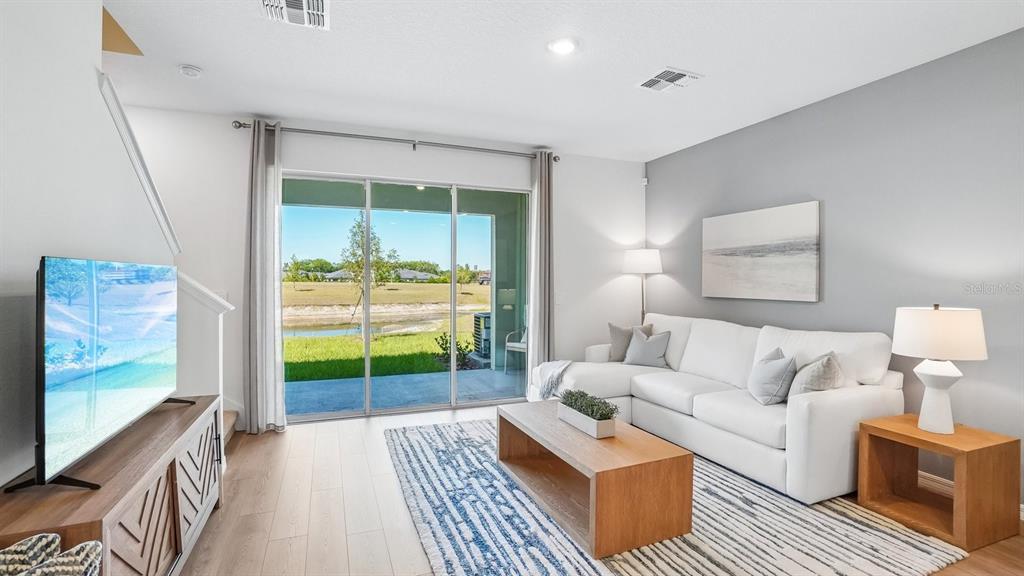 A living room features a white sectional sofa, wood coffee table, and sliding glass doors — 12607 CITRUS PARK LANE, TAMPA, FL