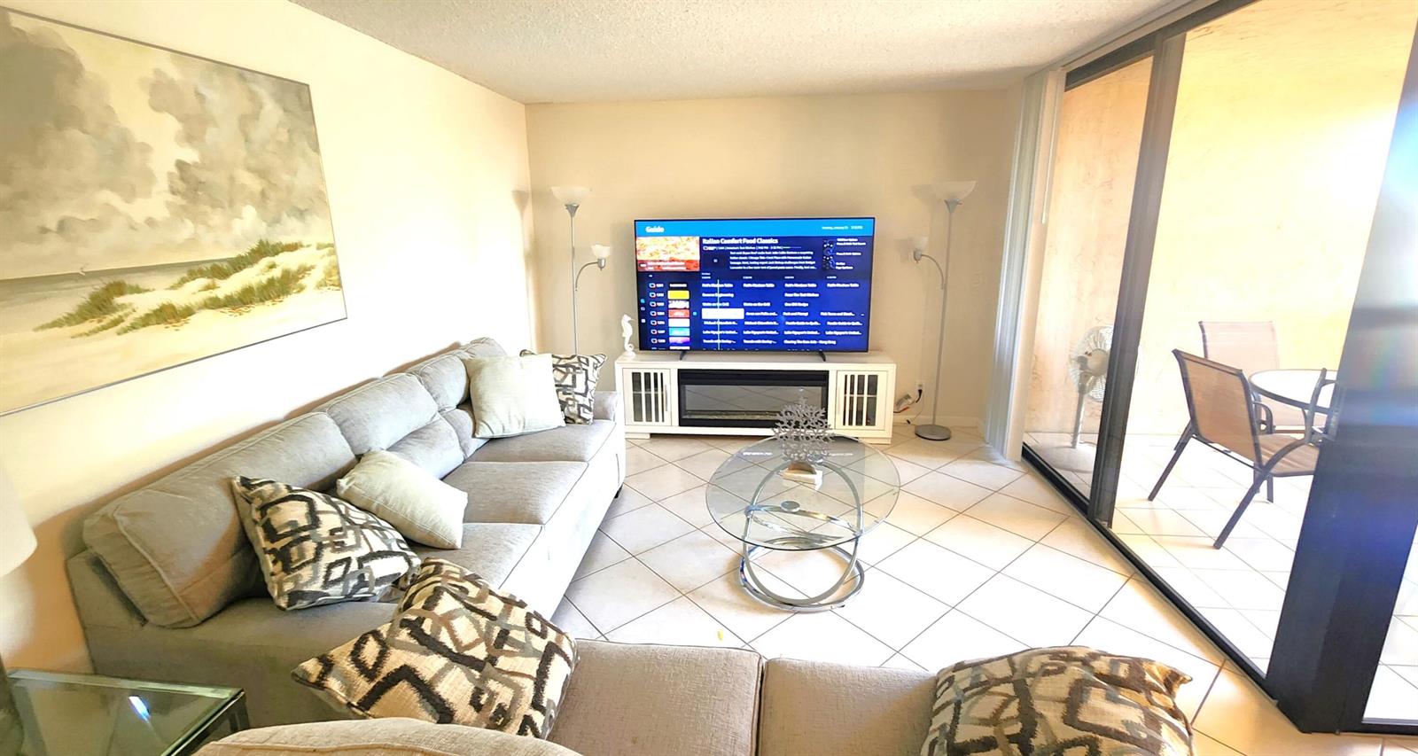 A living room features a gray sofa, a glass coffee table, and a television console — 750 Egret Circle # 6404, Delray Beach FL 33444, DELRAY BEACH, FL