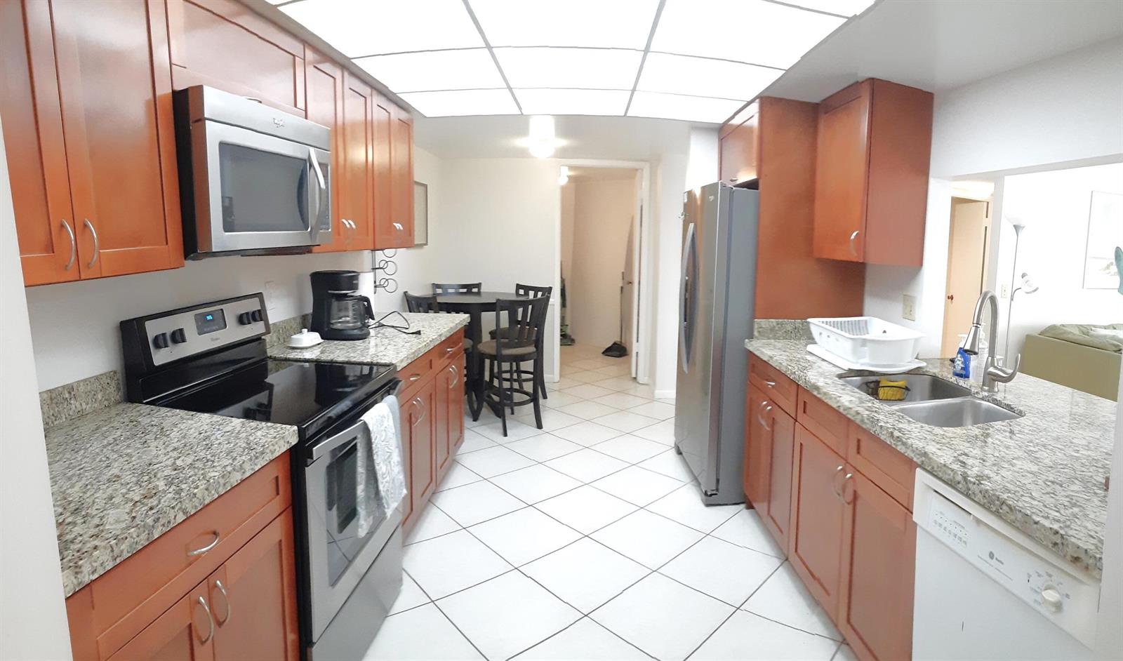 A kitchen with wood cabinets, granite countertops, stainless steel appliances, and white tile flooring — 750 Egret Circle # 6404, Delray Beach FL 33444, DELRAY BEACH, FL