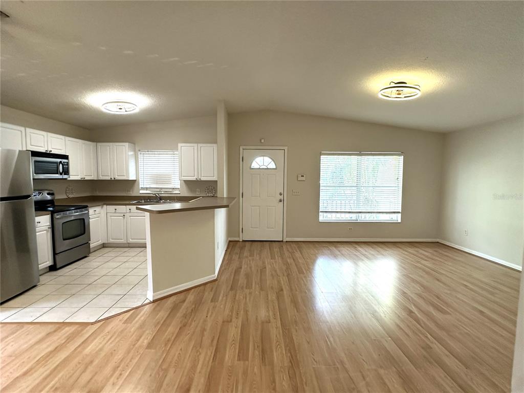 An open-concept kitchen and living area features light wood flooring, white cabinets, and stainless appliances — 1717 W NASSAU STREET UNIT A, TAMPA, FL