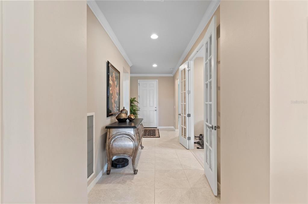A hallway features beige walls, tile flooring, a console table, and white French doors — 13825 RINUCCIO STREET, VENICE, FL
