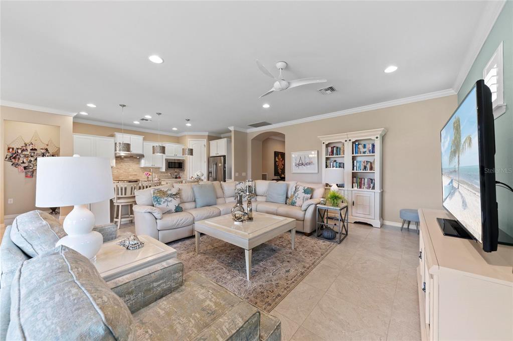 A living room with a sectional sofa, coffee table, and open kitchen in the background — 13825 RINUCCIO STREET, VENICE, FL
