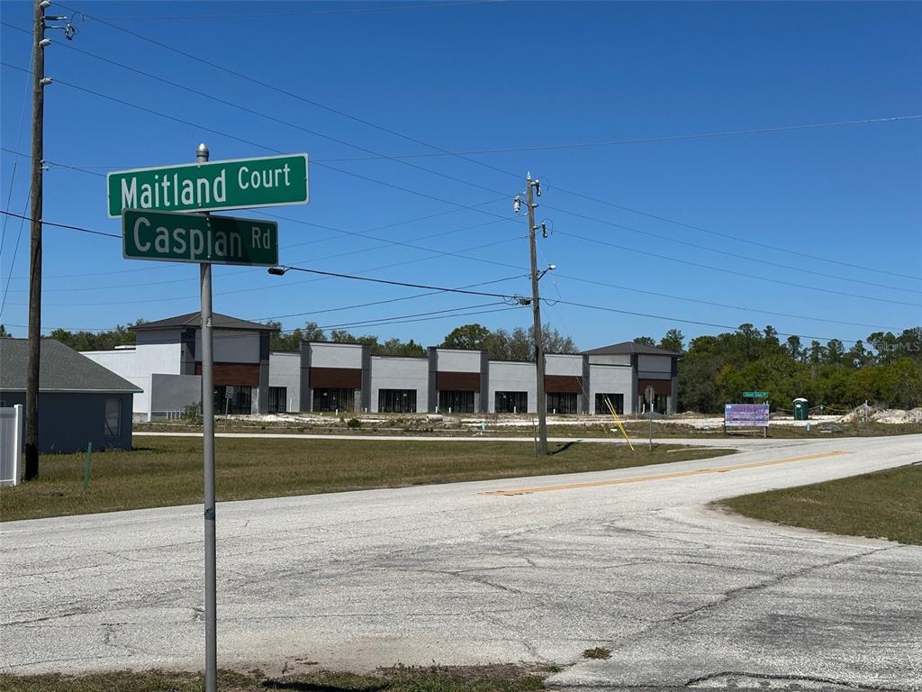 A street sign at the intersection of Maitland Court and Caspian Road faces a commercial building — 419 MAITLAND COURT, KISSIMMEE, FL