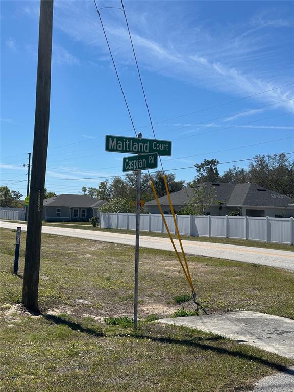 A street sign for Maitland Court and Caspian Road stands in a grassy residential area — 419 MAITLAND COURT, KISSIMMEE, FL