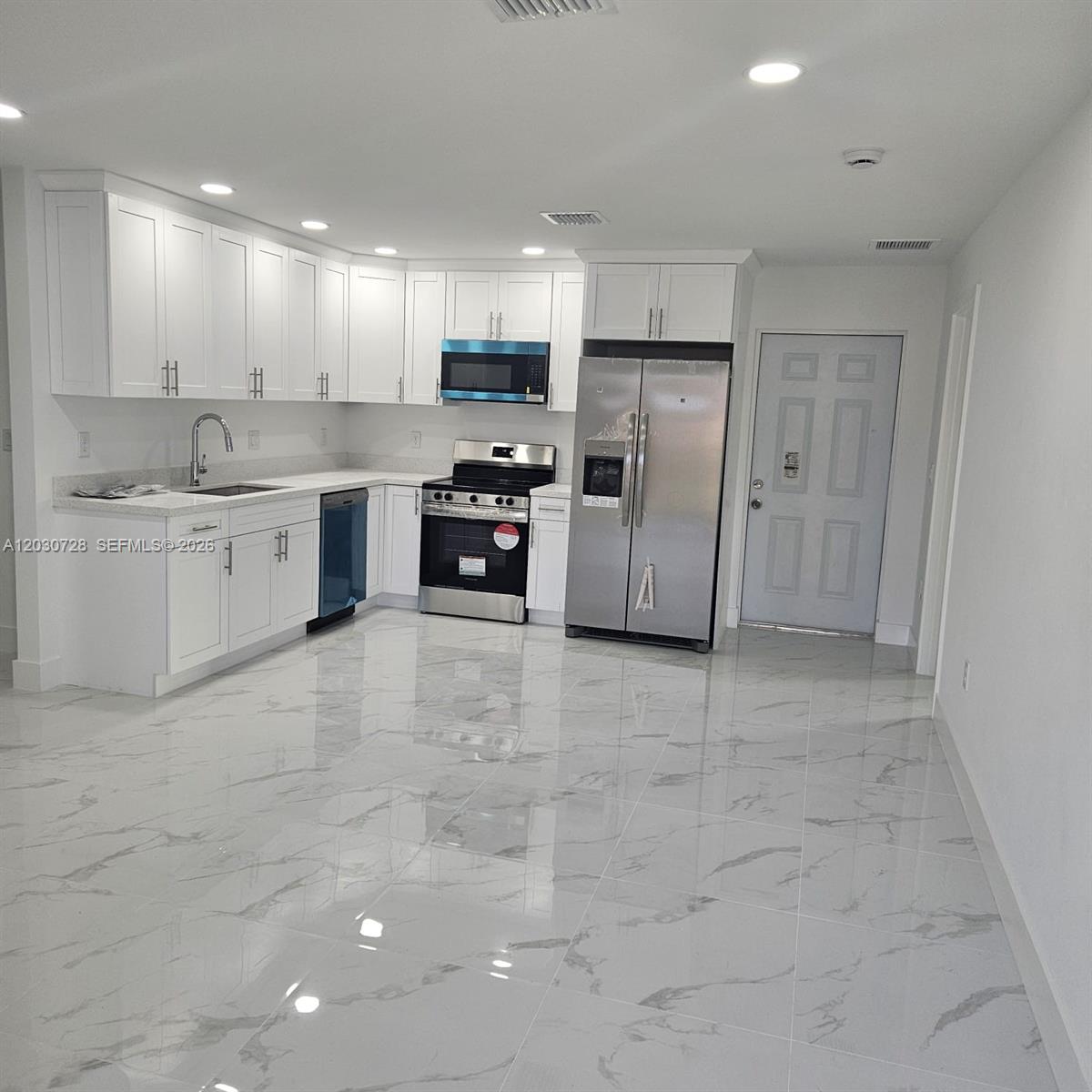 A kitchen features white cabinets, stainless steel appliances, and light-colored marble-patterned tile flooring — 3819 3rd st W, Lehigh Acres FL 33971, LEHIGH ACRES, FL