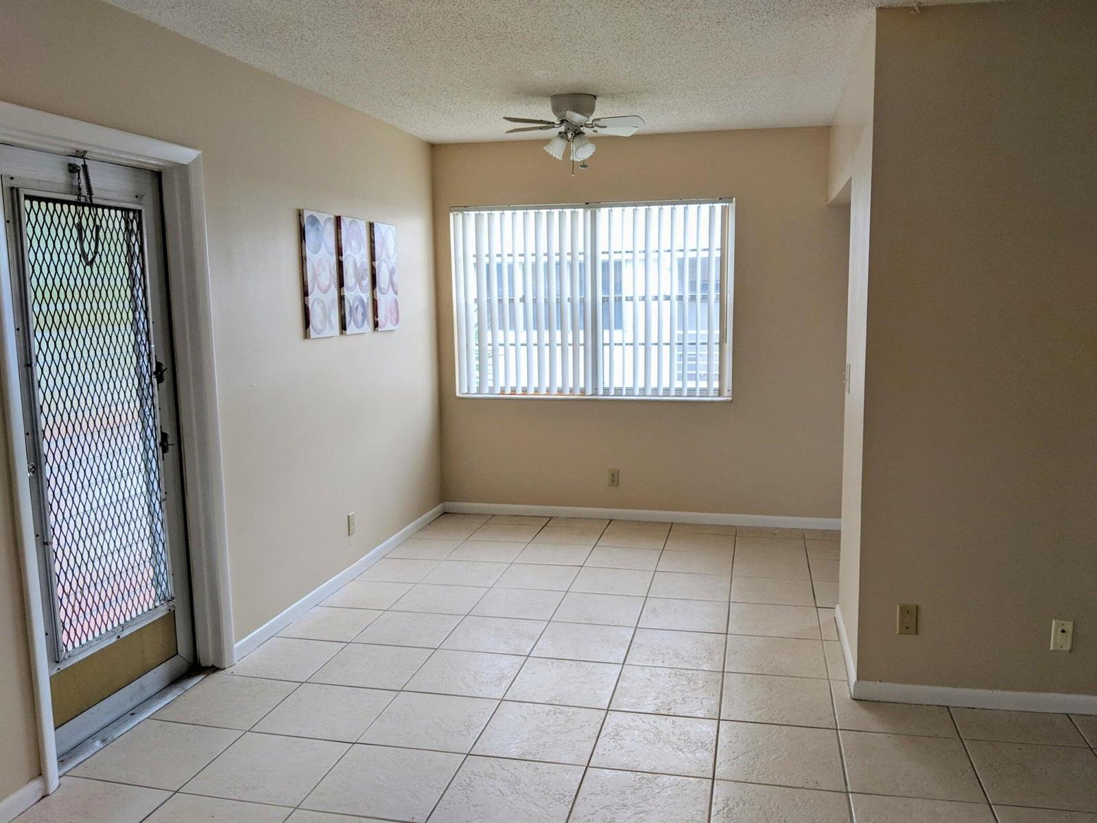 An empty room with beige walls, tile flooring, a ceiling fan, and a glass door — 288 Norwich, West Palm Beach FL 33417, WEST PALM BEACH, FL