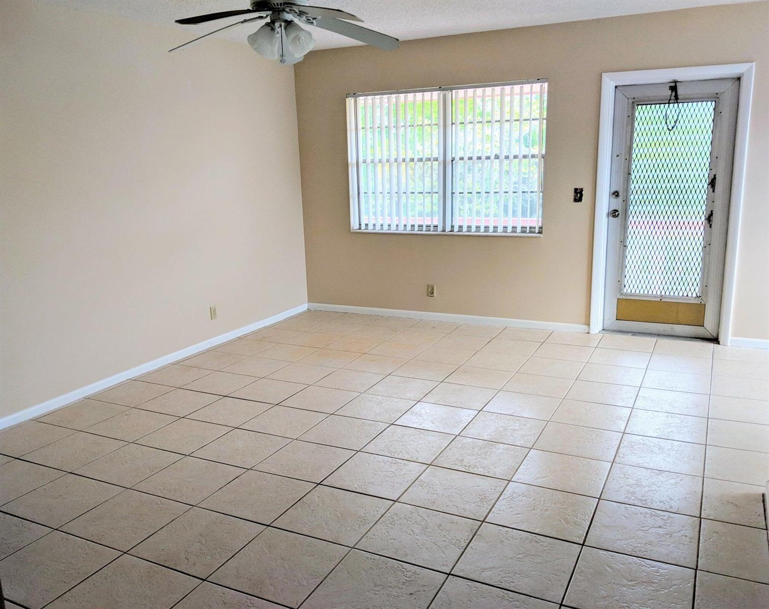 An empty room features beige walls, light-colored tile flooring, a ceiling fan, and a glass door — 288 Norwich, West Palm Beach FL 33417, WEST PALM BEACH, FL