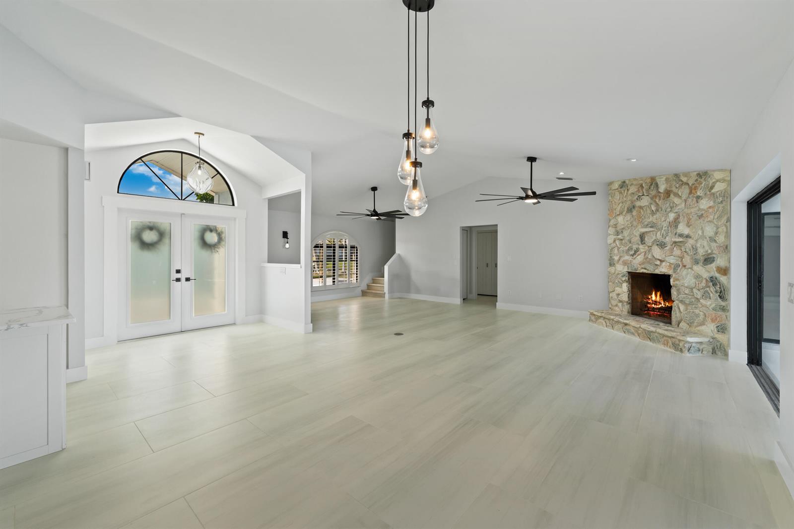 A spacious living room features light tile flooring, a stone fireplace, and vaulted ceilings — 2807 NW St Lucie Lane, Stuart FL 34994, STUART, FL