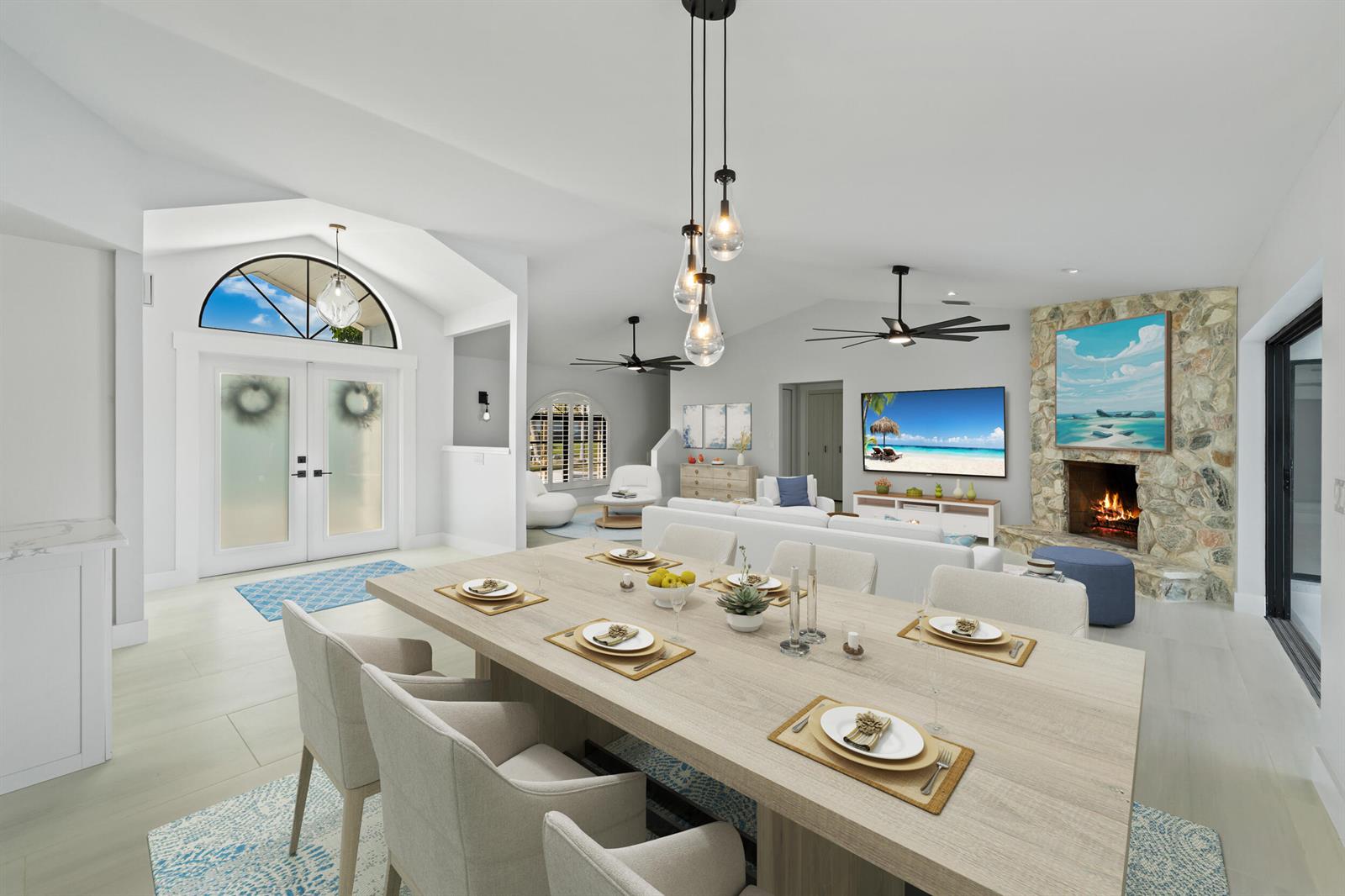 This open-concept living and dining area features a stone fireplace, vaulted ceilings, and modern lighting — 2807 NW St Lucie Lane, Stuart FL 34994, STUART, FL