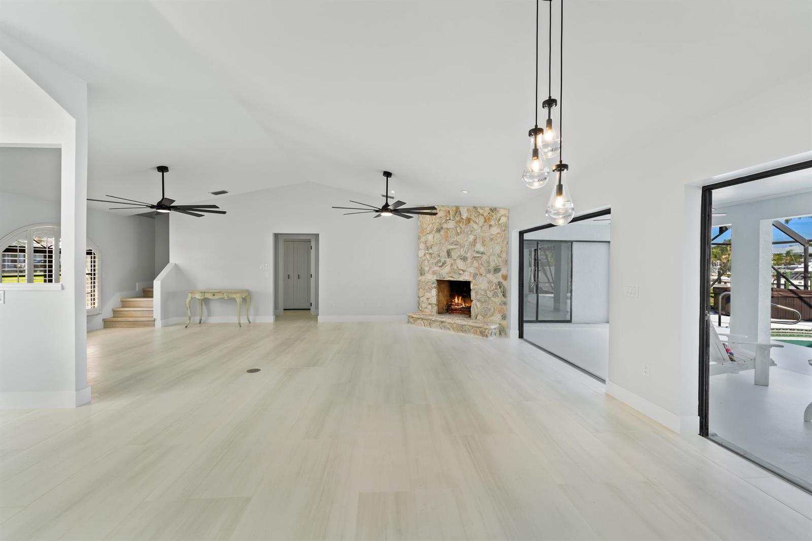 A spacious living room features light wood floors, a stone fireplace, and sliding glass doors — 2807 NW St Lucie Lane, Stuart FL 34994, STUART, FL