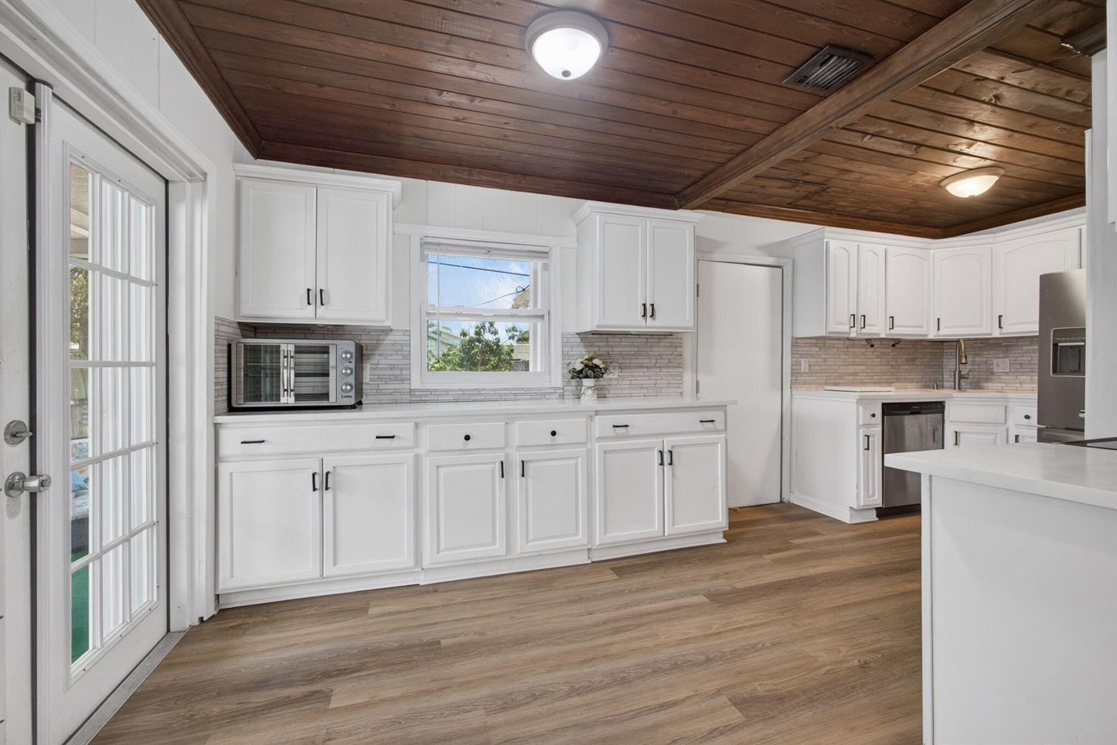 A kitchen features white cabinets, a wood-plank ceiling, and light-colored wood-look flooring — 1314 N J Street, FL 33460, FL