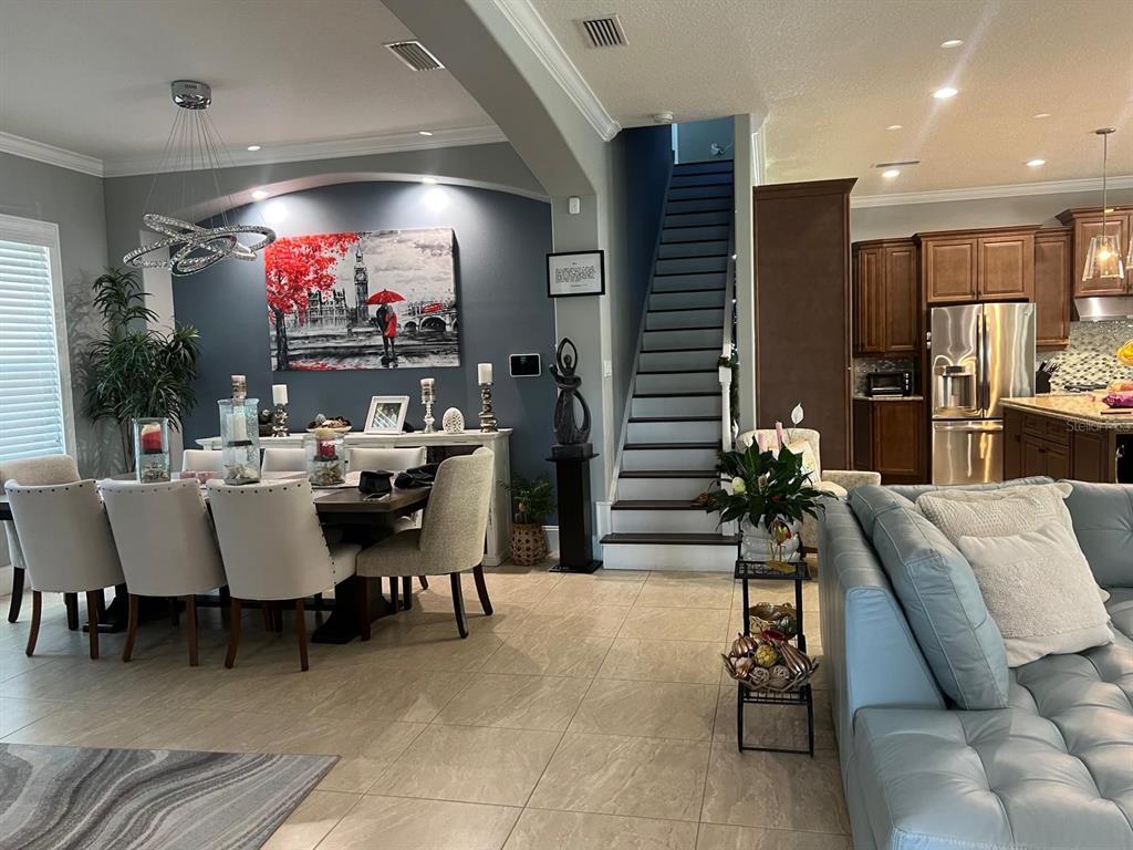 An open-concept living area features a dining room, a staircase, and a kitchen with cabinetry — 12 LIONSPAW GRAND, DAYTONA BEACH, FL