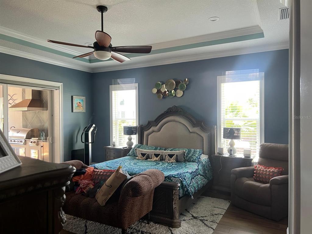 A bedroom with blue walls, a tray ceiling, a ceiling fan, and a large bed — 12 LIONSPAW GRAND, DAYTONA BEACH, FL