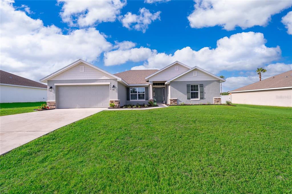 A single-story suburban house with a gray stucco exterior, a two-car garage, and a lawn — 226 NW 44TH STREET, OCALA, FL
