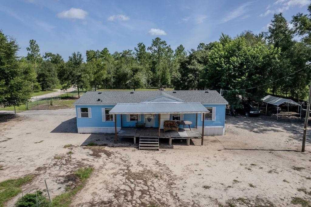 An aerial view of a light blue manufactured home with a front porch and metal roof — 7491 NE 101ST COURT, BRONSON, FL