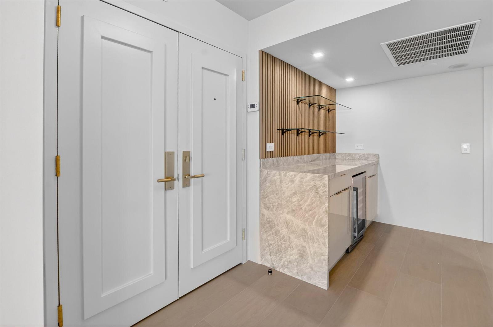 A wet bar with marble counters and wood slat wall accents sits beside double doors — 2800 S Ocean Boulevard # 23c, Boca Raton FL 33432, BOCA RATON, FL