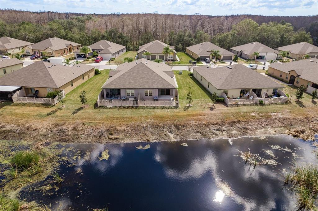 An aerial view of suburban houses with fenced backyards bordering a pond and wooded area — 13387 CREST LAKE DRIVE, HUDSON, FL