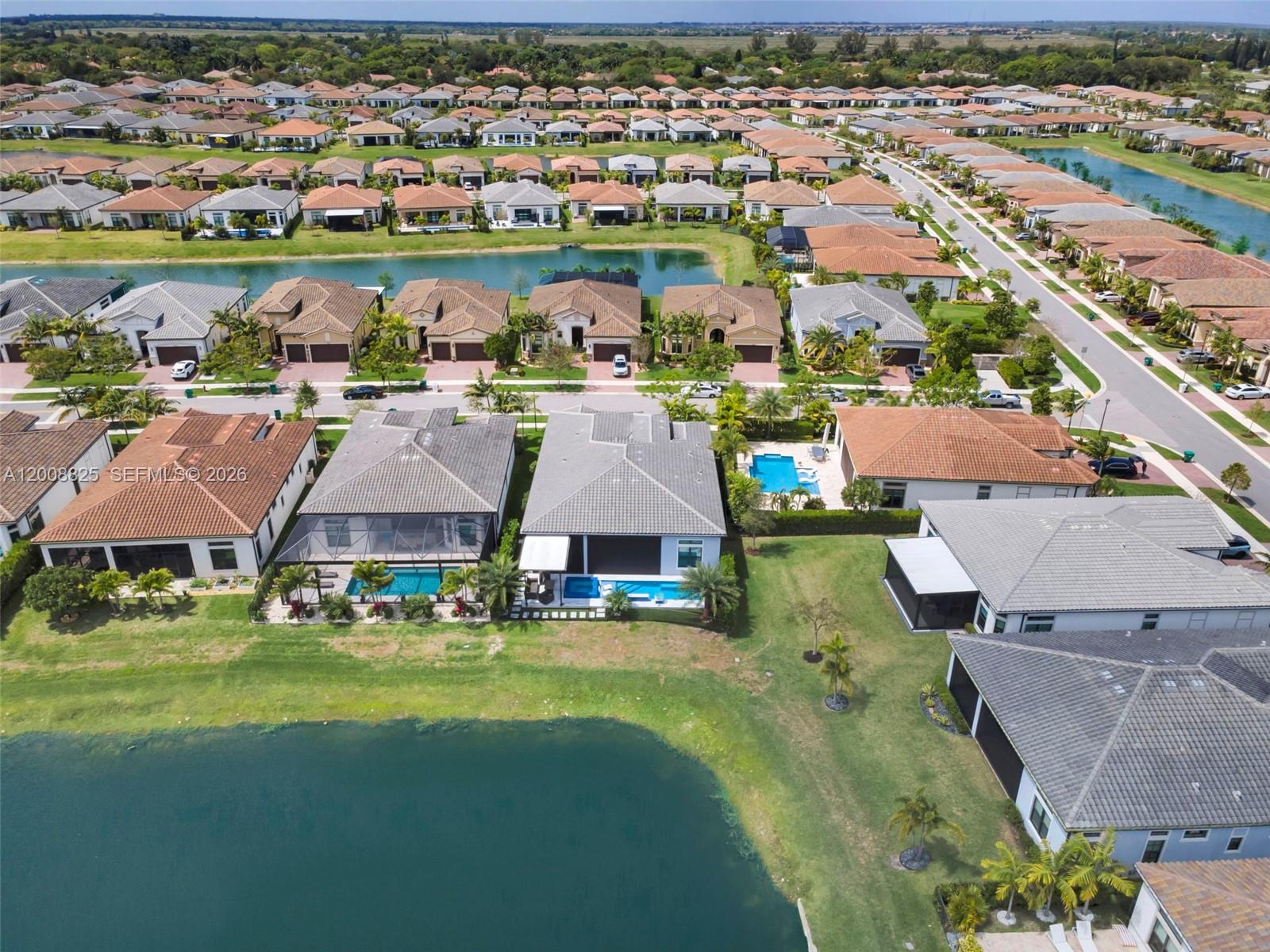 An aerial view shows a suburban neighborhood with houses, swimming pools, and a large lake — 8022 Deer Lake Ct, Parkland FL 33067, PARKLAND, FL
