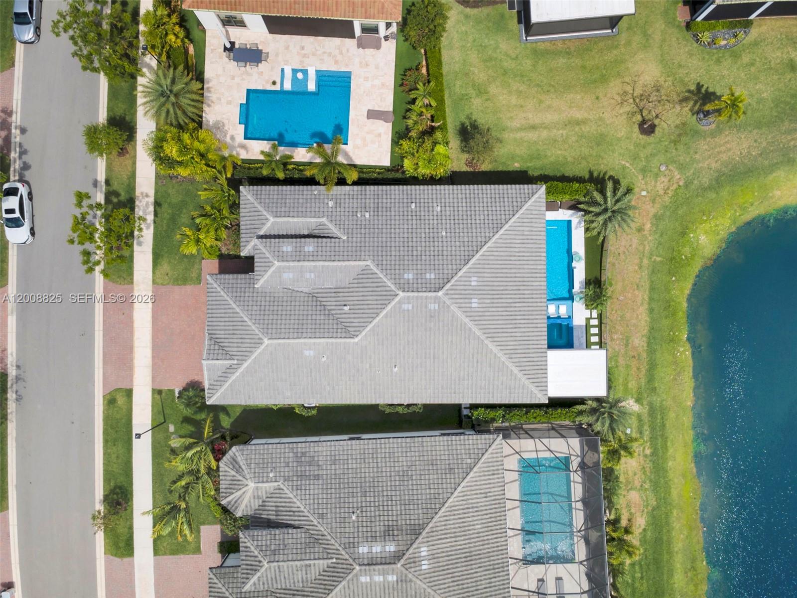 Aerial view of three residential homes with pools and a lake in a suburban neighborhood — 8022 Deer Lake Ct, Parkland FL 33067, PARKLAND, FL