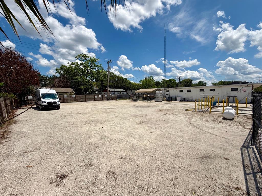 A large, unpaved gravel lot features a white van, a storage structure, and perimeter fencing — 414 W 9TH STREET, SANFORD, FL