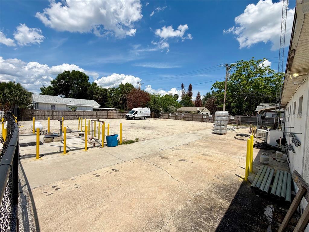 A paved outdoor lot features yellow bollards, a white van, and a wooden fence — 414 W 9TH STREET, SANFORD, FL