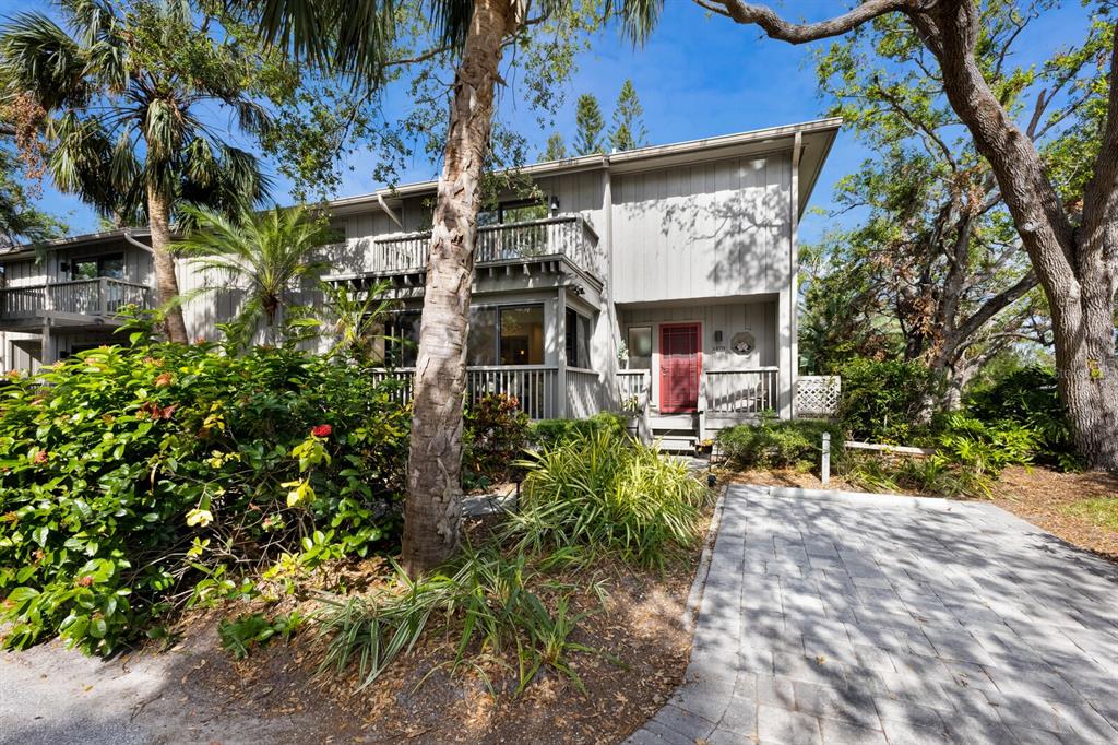 A two-story gray townhouse features a red front door, a balcony, and a paved walkway — 1479 LANDINGS CIRCLE UNIT 41, SARASOTA, FL