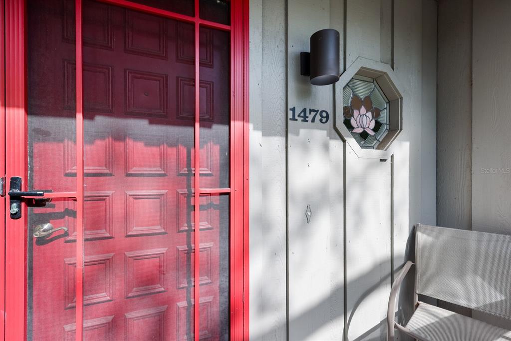 A red screen door sits next to a wall with house numbers and a window — 1479 LANDINGS CIRCLE UNIT 41, SARASOTA, FL