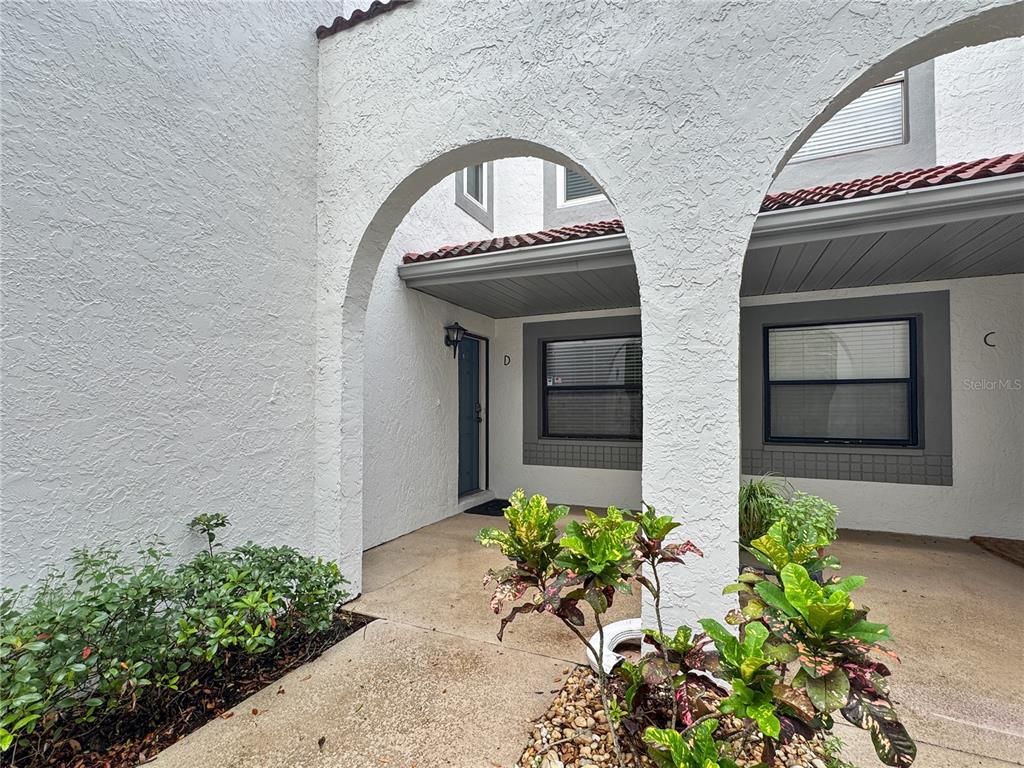 The exterior of a residential building features two arched entryways leading to units labeled D and C — 484 SANTA CRUZ PLACE NE UNIT D, ST PETERSBURG, FL