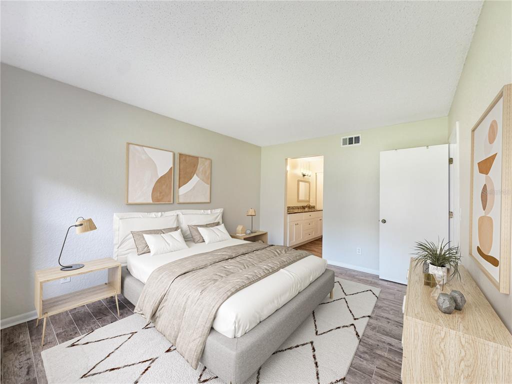 A bedroom features a gray bed, a white rug, light wood furniture, and an attached bathroom — 484 SANTA CRUZ PLACE NE UNIT D, ST PETERSBURG, FL