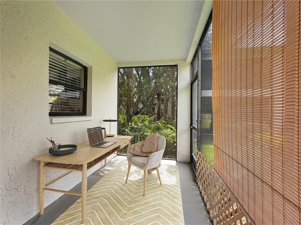 A sunroom features a desk, a chair, a chevron rug, and a large screened window — 484 SANTA CRUZ PLACE NE UNIT D, ST PETERSBURG, FL