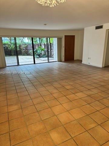 A spacious room with terracotta tile flooring and large sliding glass doors leading outside — 9001 SW 94 ST # 113, Miami FL 33176, MIAMI, FL