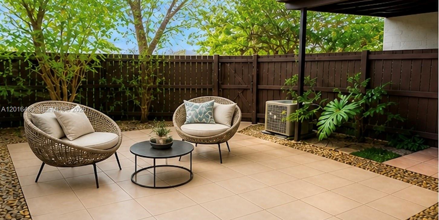 A patio features two wicker chairs, a small round table, and a brown privacy fence — 9001 SW 94 ST # 113, Miami FL 33176, MIAMI, FL