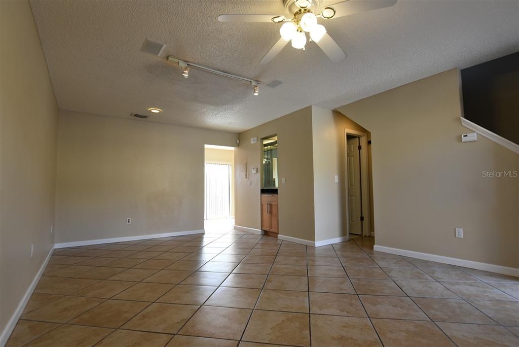 An open living area features tan tile flooring, beige walls, and a ceiling fan — 3374 CEDAR SPRINGS PLACE UNIT 155, WINTER PARK, FL