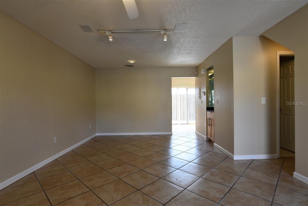An empty room with tan walls, tile flooring, a ceiling fan, and a wet bar — 3374 CEDAR SPRINGS PLACE UNIT 155, WINTER PARK, FL