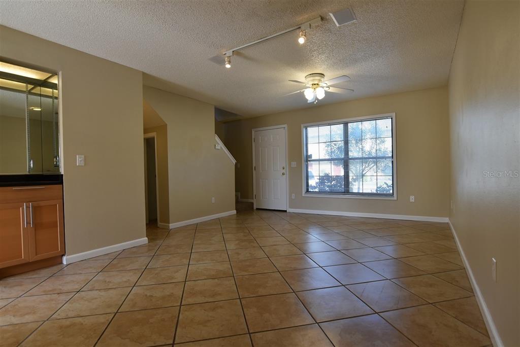 A living room with tan walls, tile flooring, a ceiling fan, and a front door — 3374 CEDAR SPRINGS PLACE UNIT 155, WINTER PARK, FL