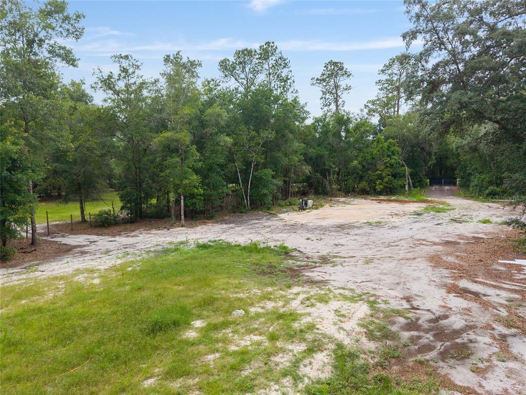 A cleared, sandy lot sits in front of a dense forest under a blue sky — 261 ASHLEY LAKE DRIVE, MELROSE, FL