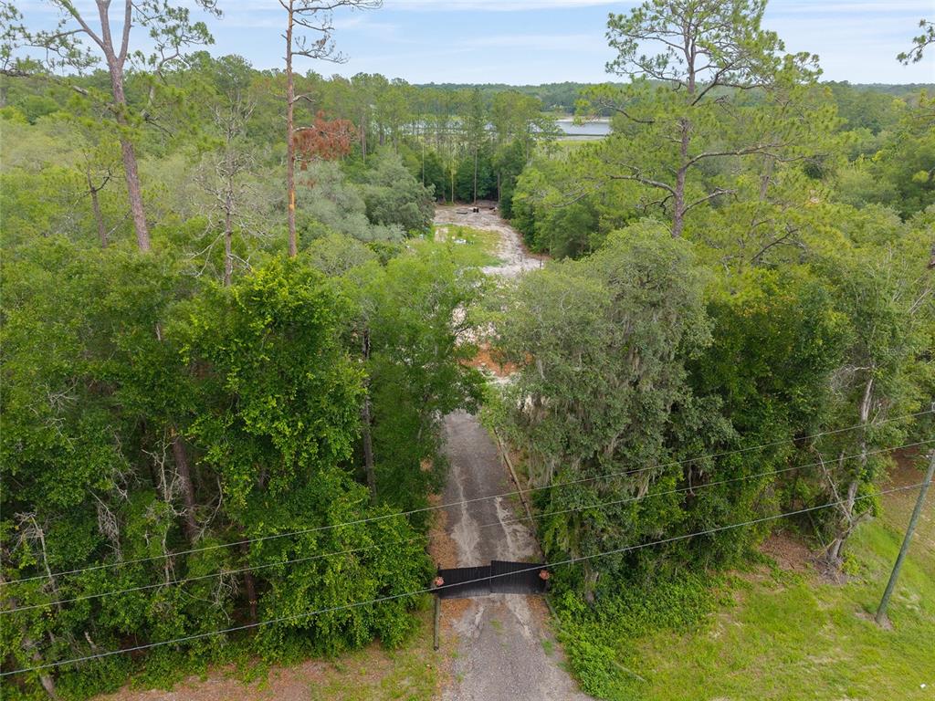 An aerial view shows a gated gravel driveway leading to a cleared lot among trees — 261 ASHLEY LAKE DRIVE, MELROSE, FL