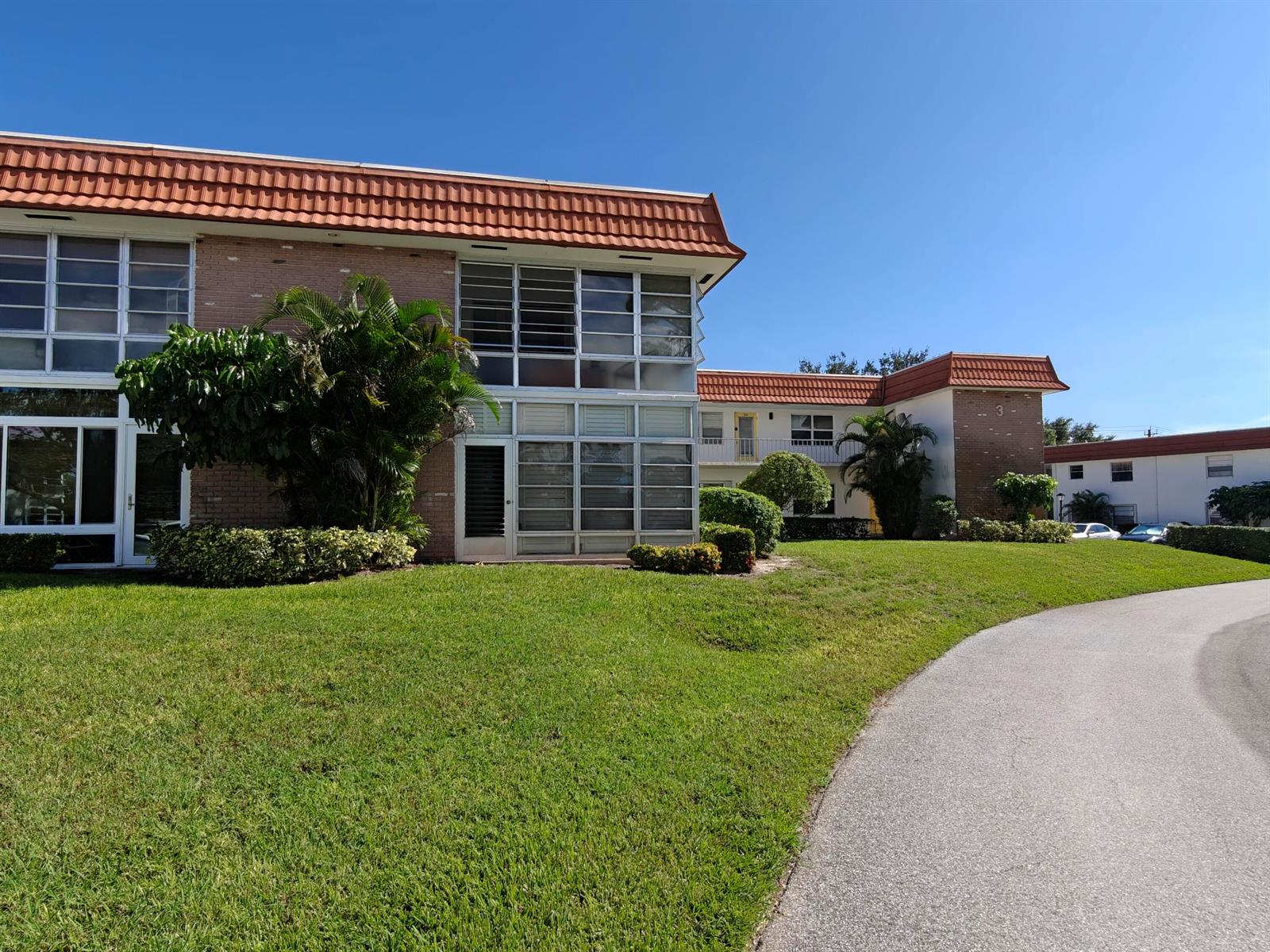 A two-story apartment building with brick siding and a red tile roof sits near a road — 1225 NW 21st Street # 311, Stuart FL 34994, STUART, FL