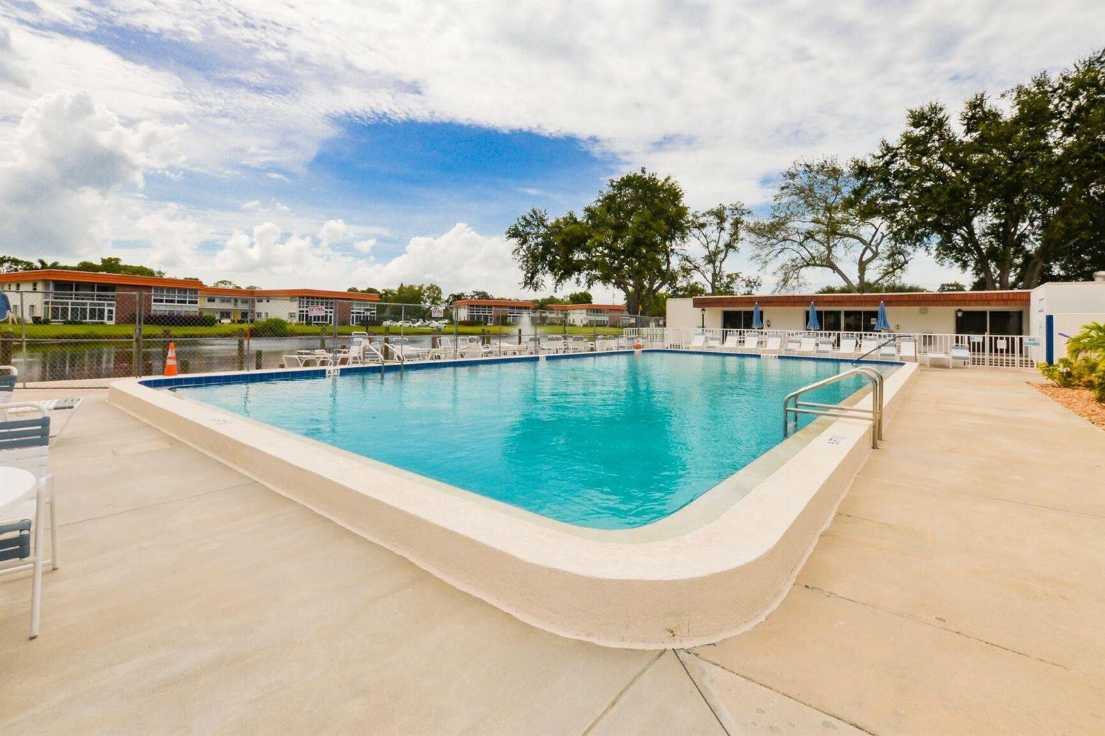 An outdoor swimming pool with a concrete deck sits in front of apartment buildings — 1225 NW 21st Street # 311, Stuart FL 34994, STUART, FL