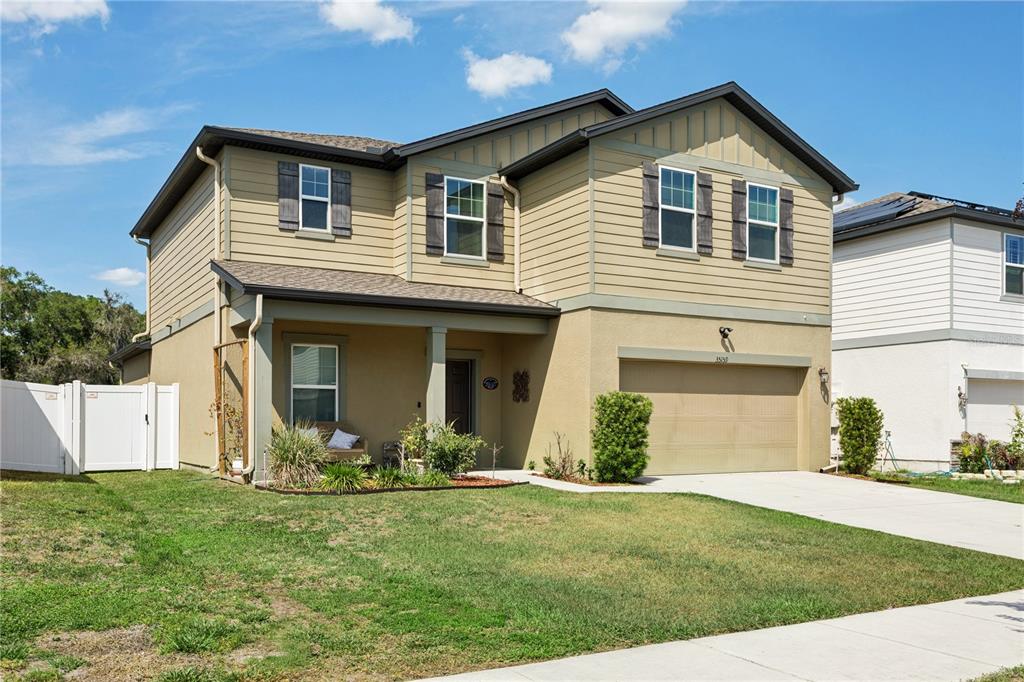 A two-story house with tan siding, a two-car garage, and a covered front porch — 35159 DAISY MEADOW LOOP, ZEPHYRHILLS, FL