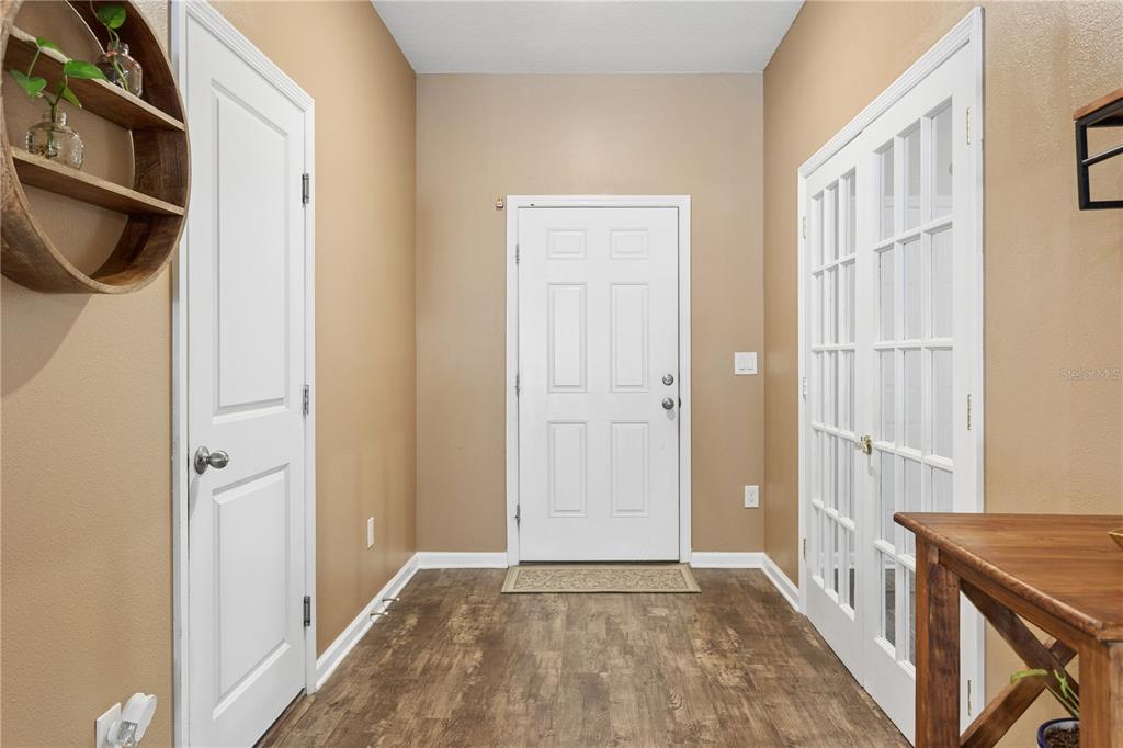 An entryway features tan walls, wood-look flooring, a white front door, and two interior doors — 35159 DAISY MEADOW LOOP, ZEPHYRHILLS, FL