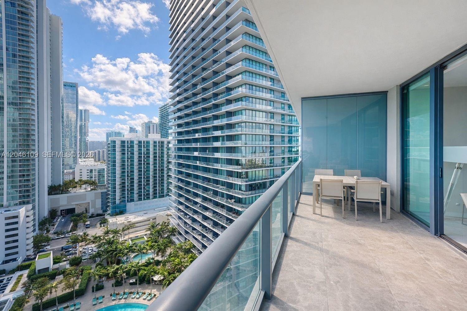 A balcony with a dining set overlooks a city skyline and a swimming pool area — 650 NE 32nd St # 2005, Miami FL 33137, MIAMI, FL